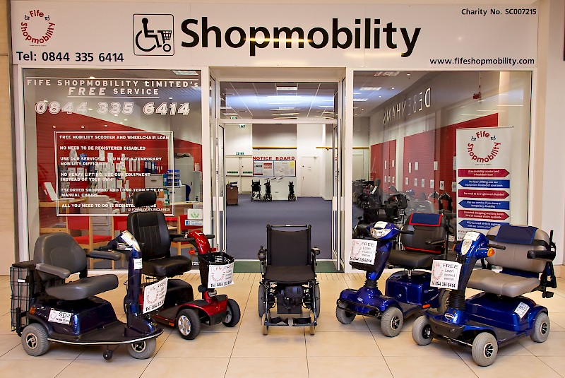 Entrance of Fife Shopmobility with several mobility scooters on display inside and outside the shop.
